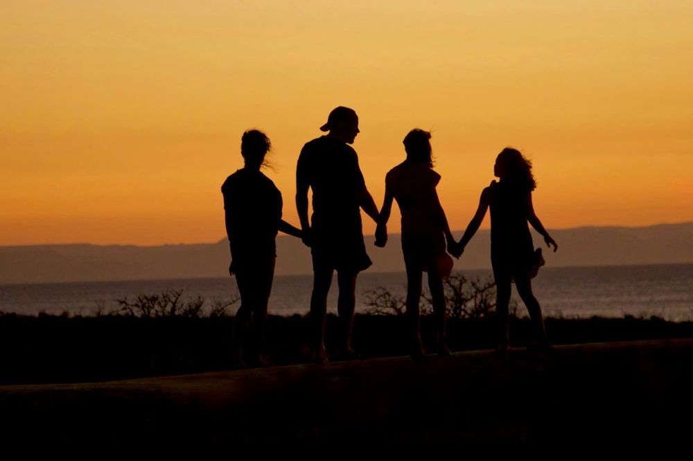 Familia tomada de la mano al atardecer